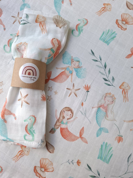 Close up of muslin square with marine creatures and mermaids pattern in pastel colours