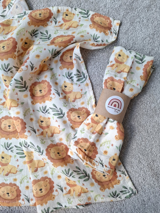 Fully spread lion cub muslin square next to rolled muslin with matching lion pattern
