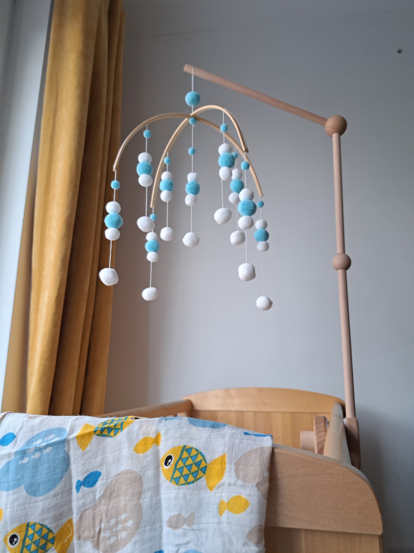 Blue and white pom pom mobile above baby cot