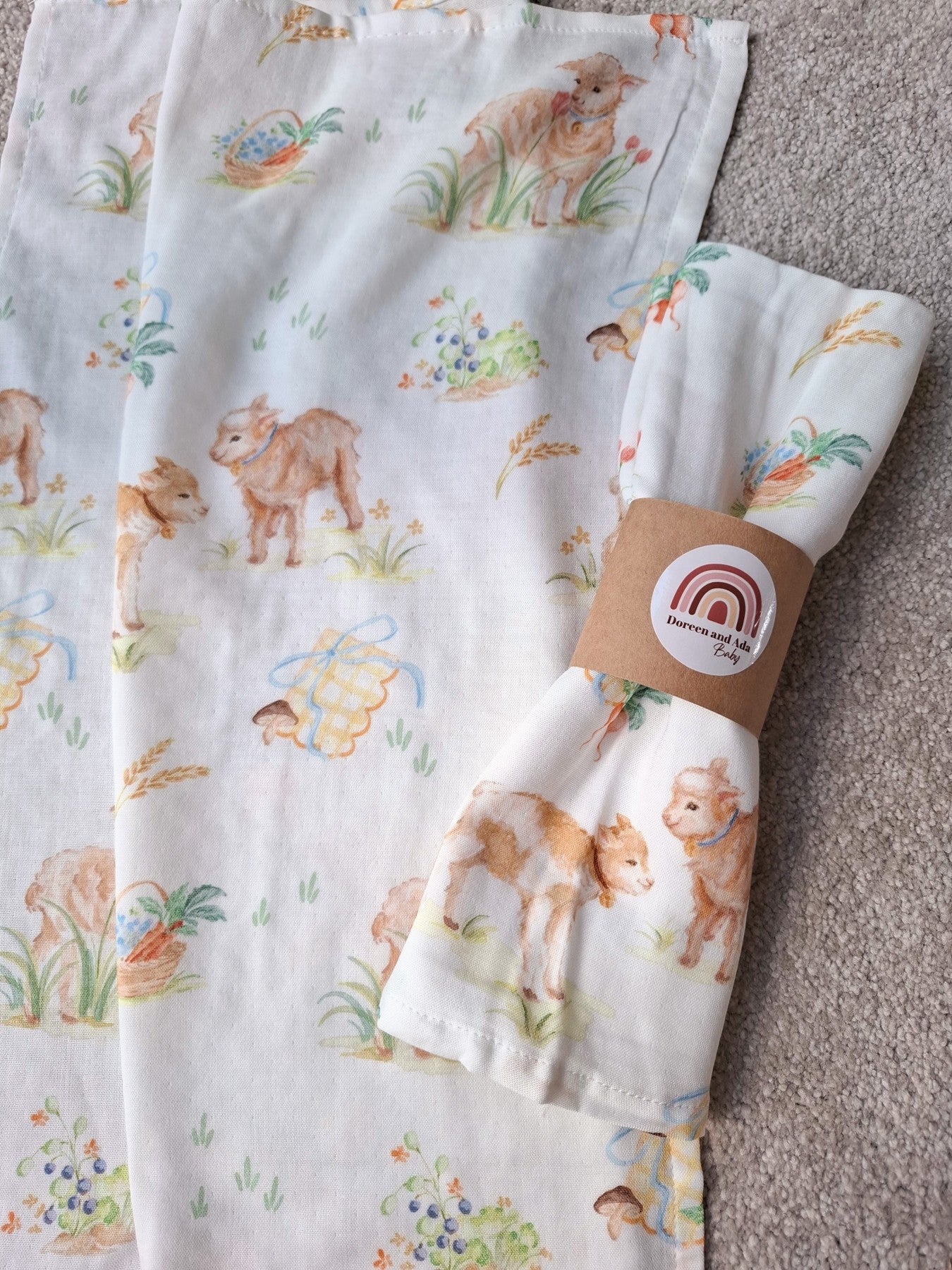 Muslin square flat with rolled muslin square on top showing lamb and garden harvest design