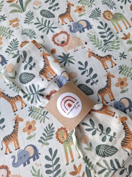 Close-up of bundled muslin square showing animal and foliage print with giraffes, lions, elephants and leaves
