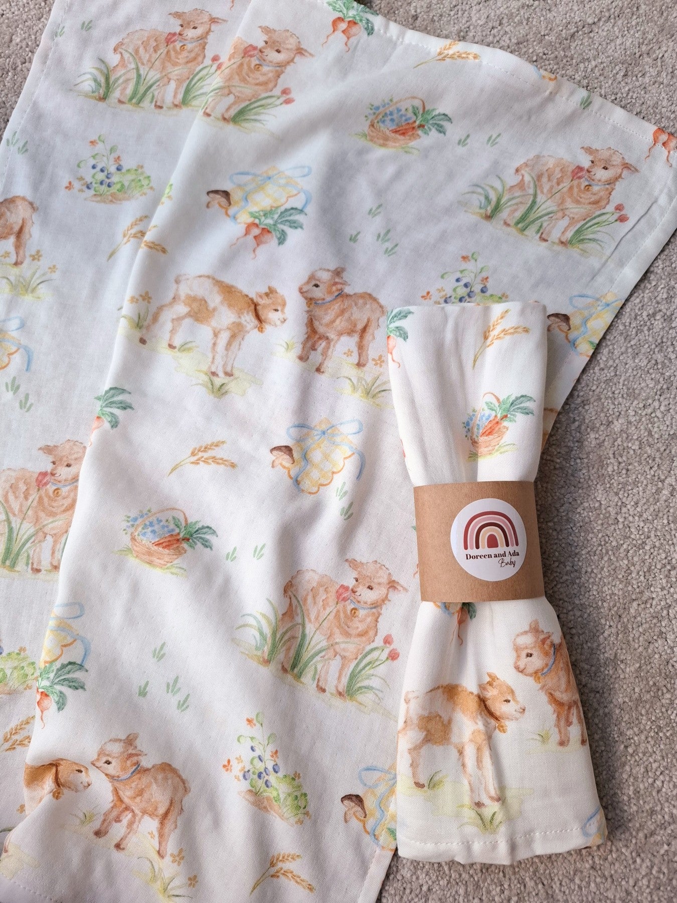 Flat muslin square fabric showing repeating lamb and garden basket pattern alongside rolled muslin square