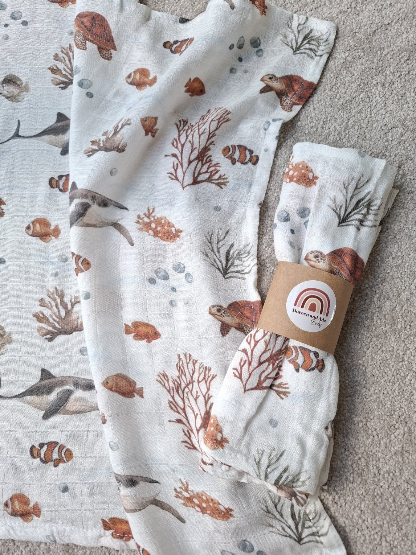 Rolled Ocean Friends muslin square showing turtles and coral design on soft white cotton background