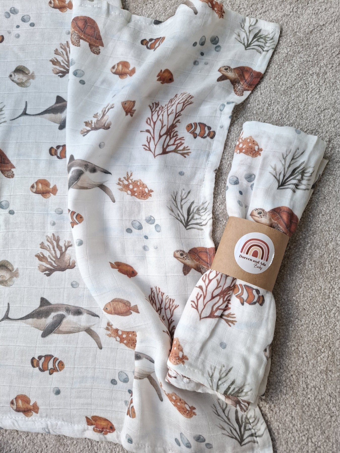 Close-up of ocean themed muslin square with coral, clownfish and turtles on white super soft cotton