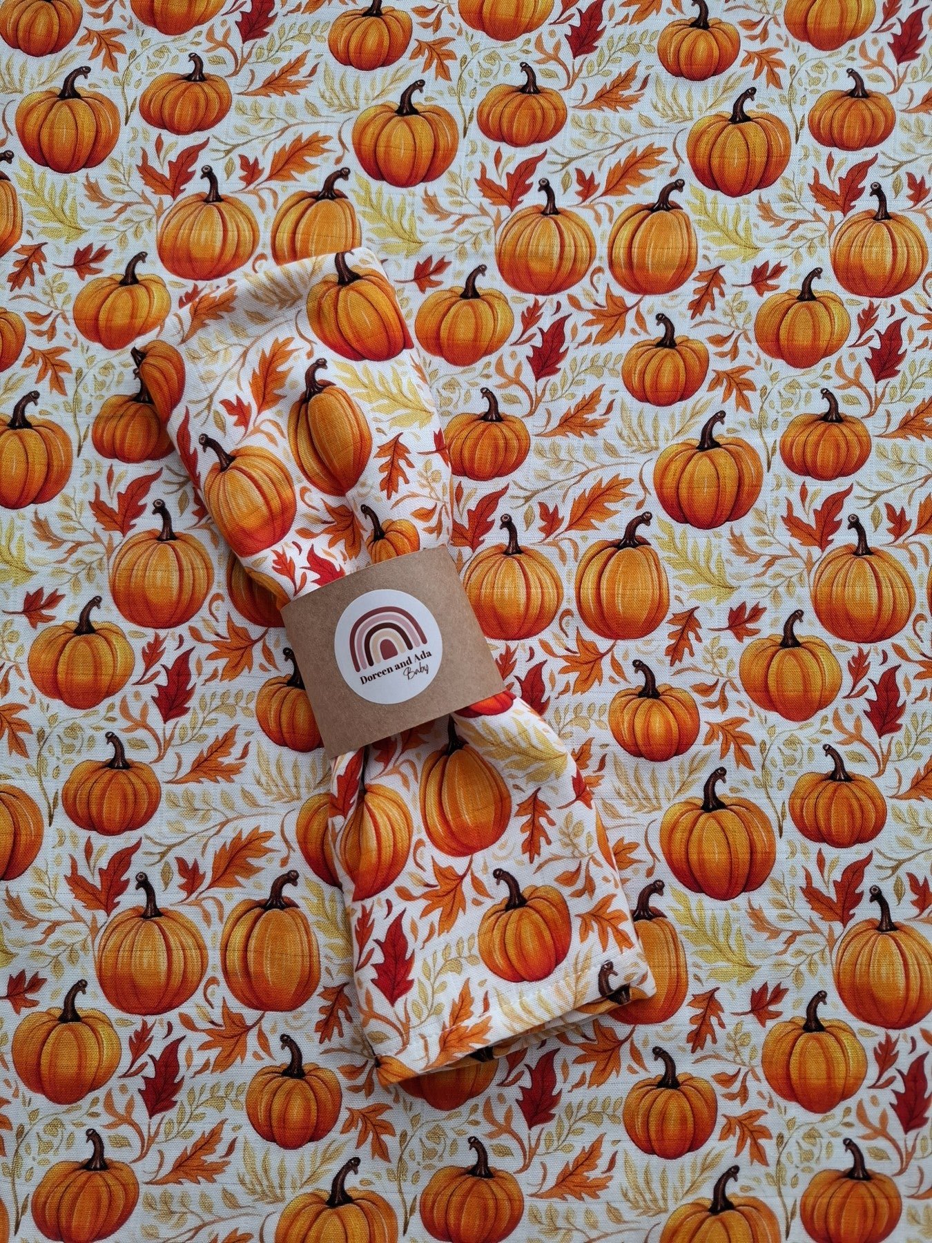 Muslin square featuring bright orange pumpkins and autumn leaves pattern