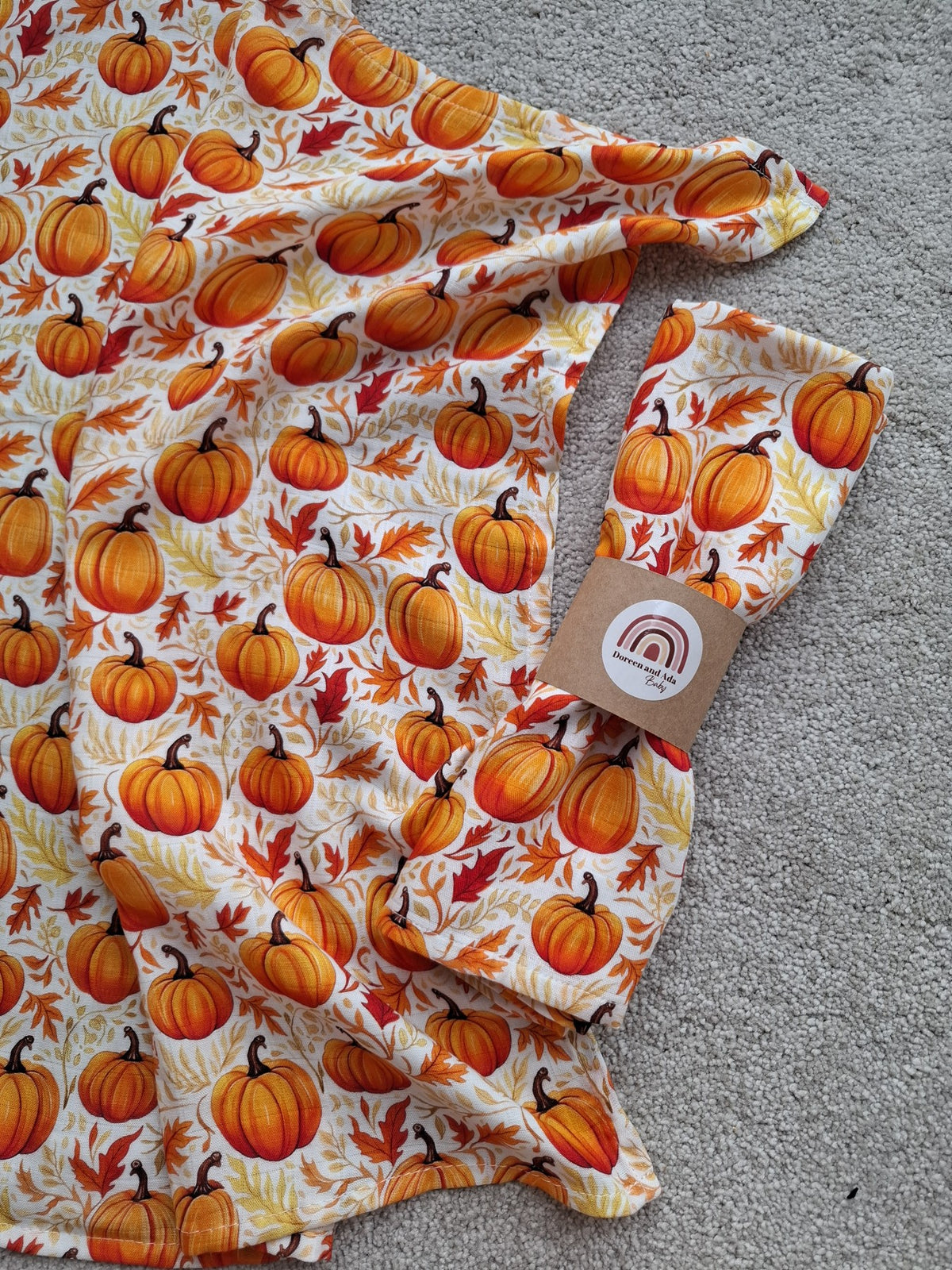 Muslin square laid flat showing vibrant orange pumpkins and leaves pattern