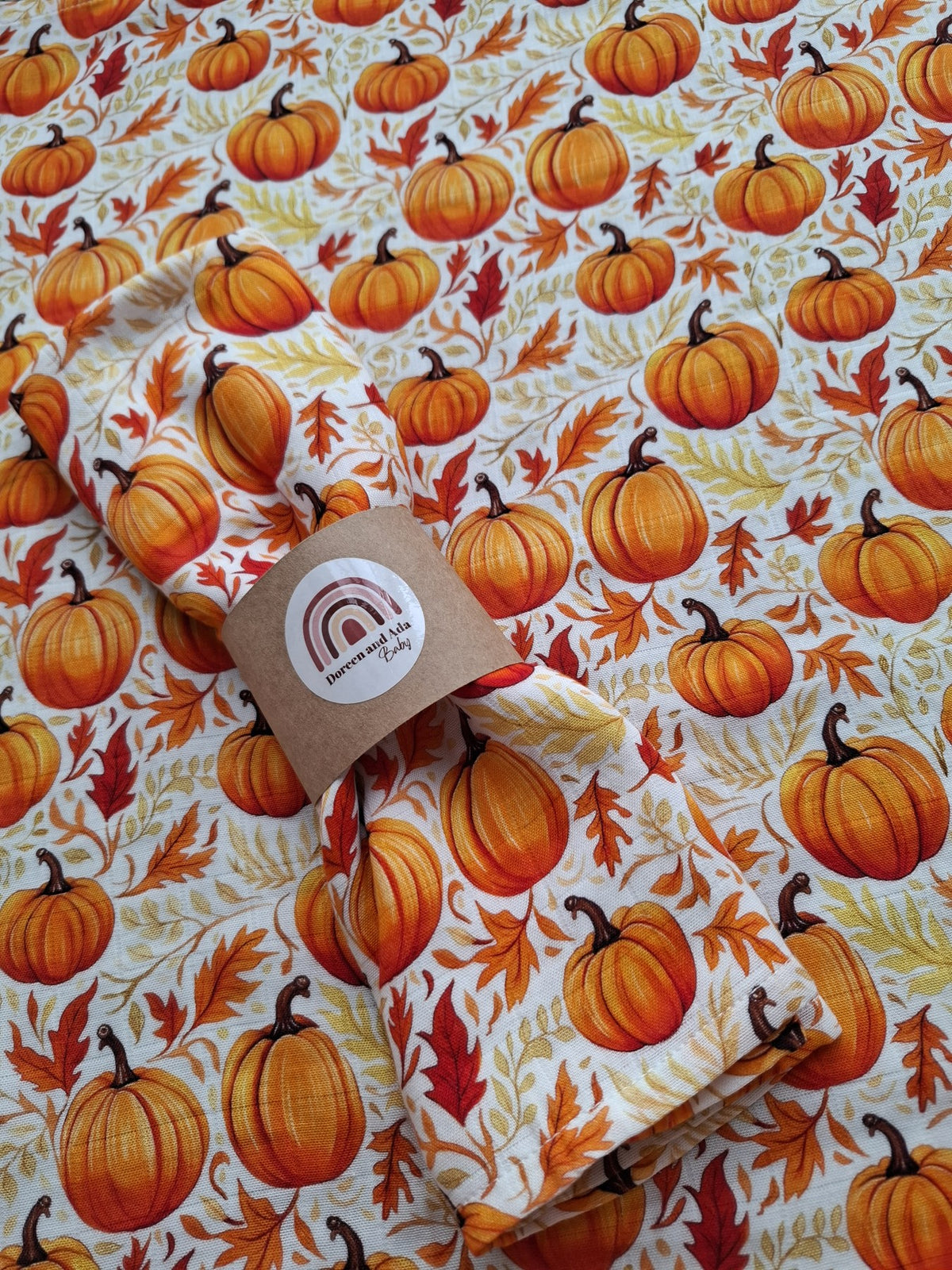 Close-up of folded muslin square with pumpkin print on white background