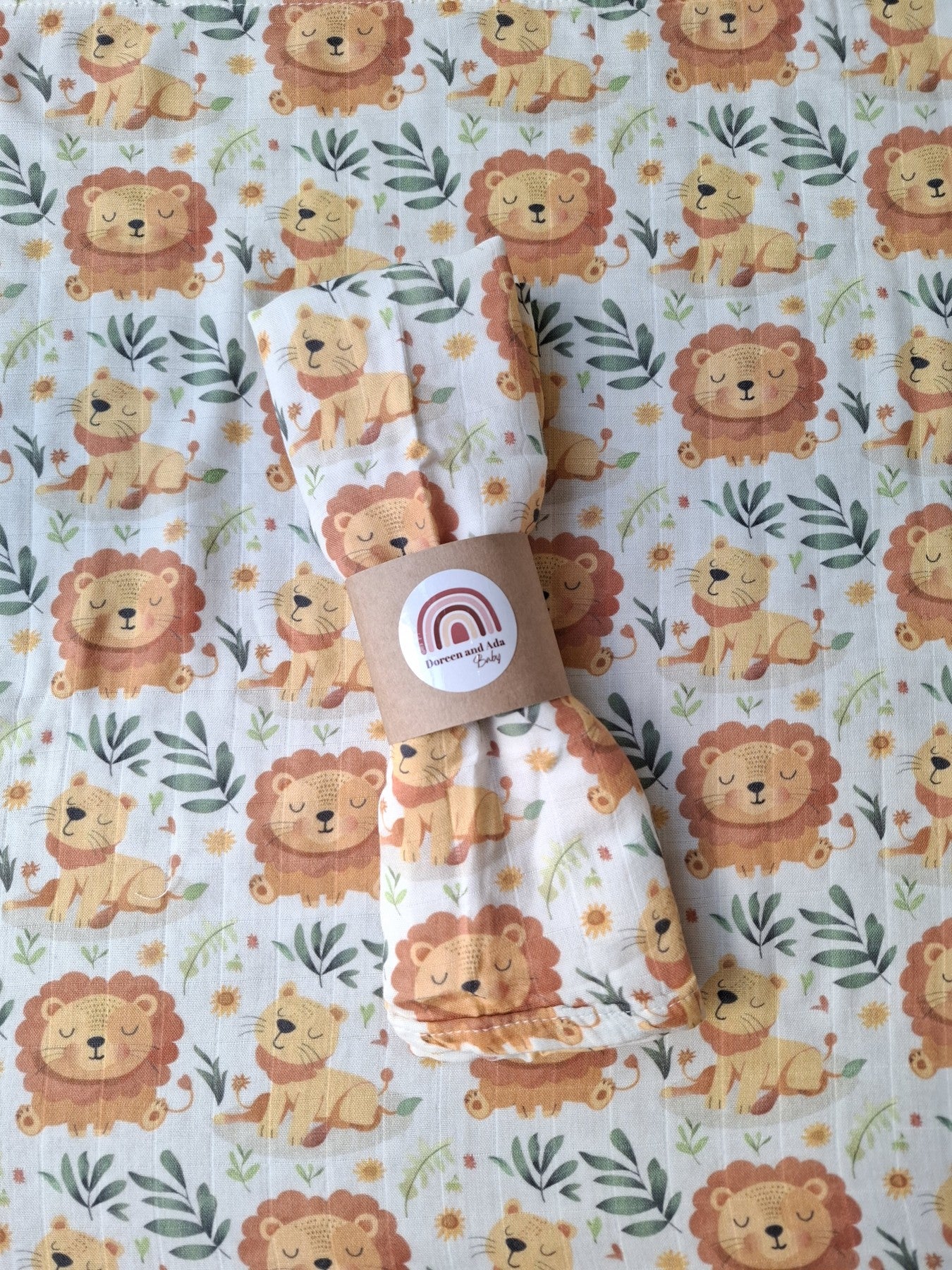 Close-up of sleepy lion cub muslin square rolled and placed on matching lion fabric