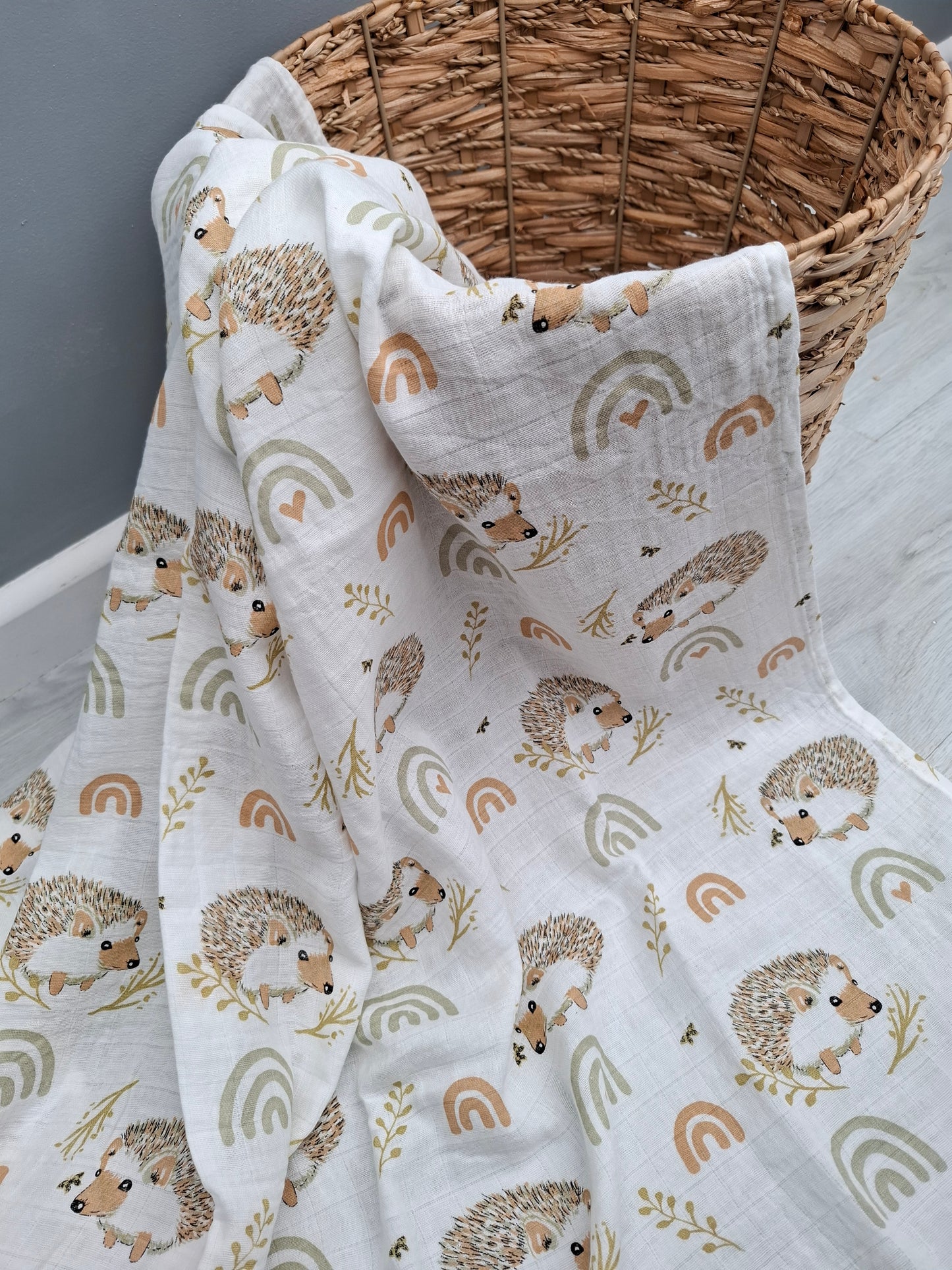 Fabric with hedgehog pattern draped over a woven basket on a gray surface