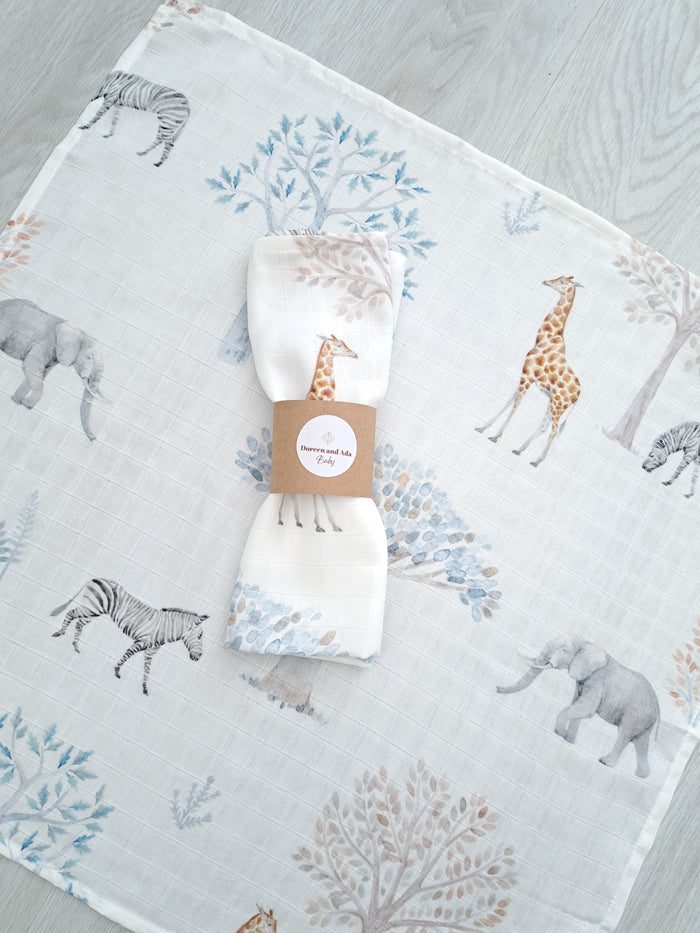 A cotton and bamboo muslin square with an animal pattern, featuring giraffes and elephants, and a price tag attached.
