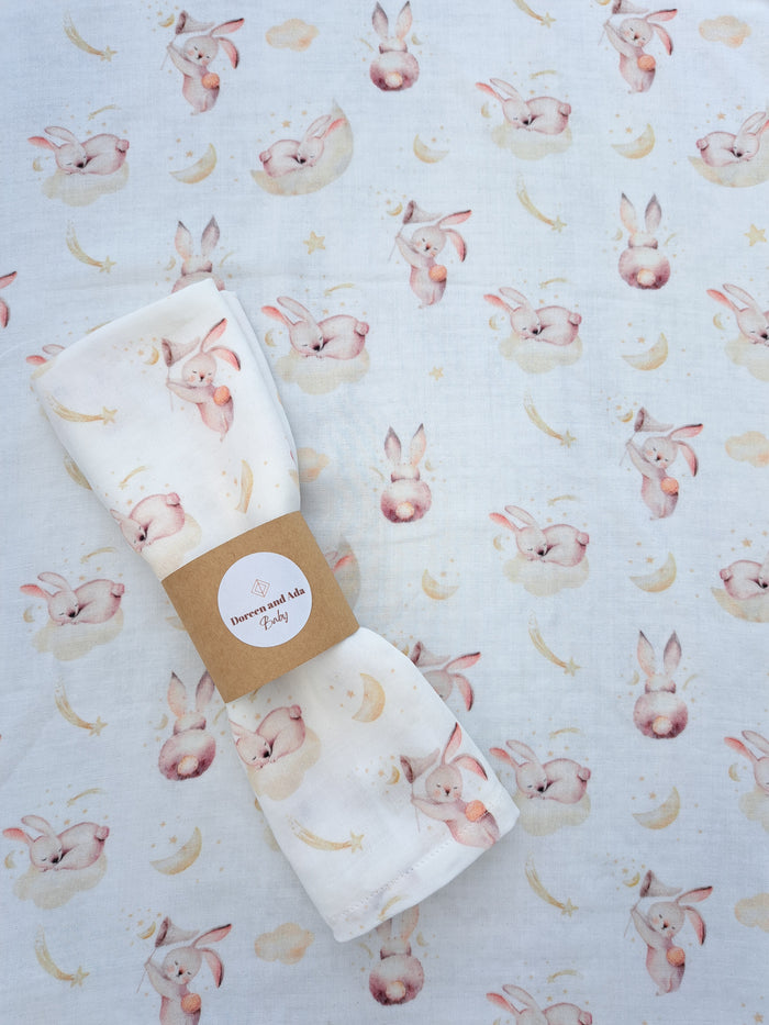 A muslin square with a pattern of rabbits and clouds, presented with a brand tag.