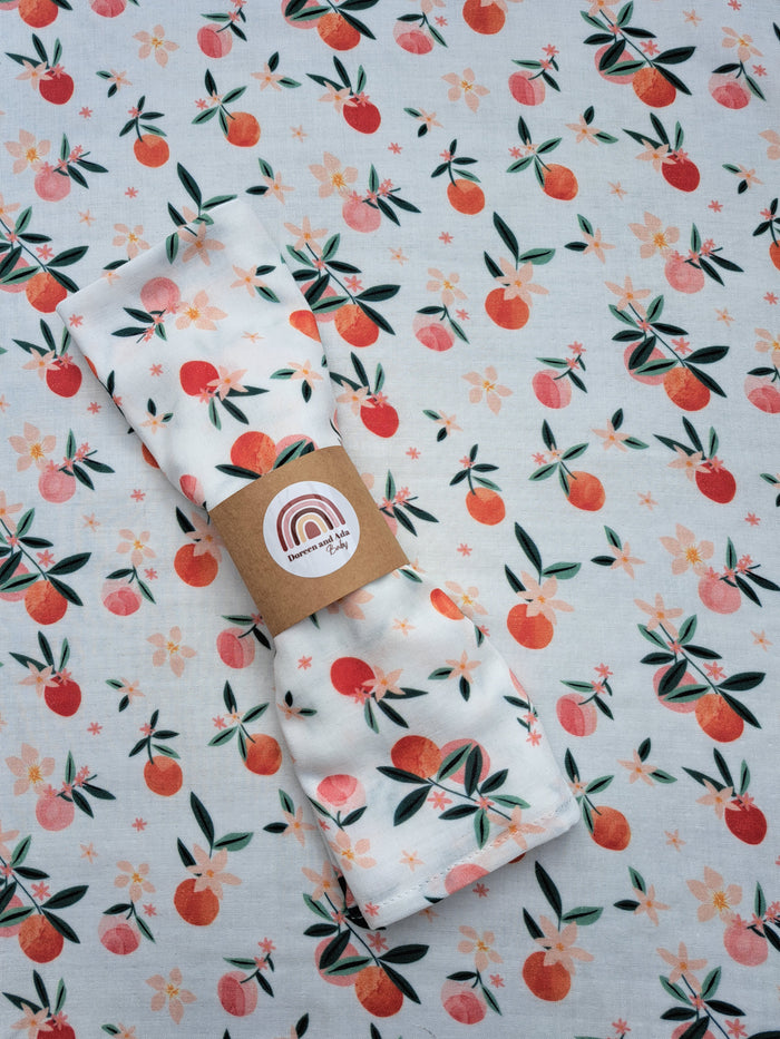 Peaches print organic cotton muslin square with fresh fruit and leaves design for babies