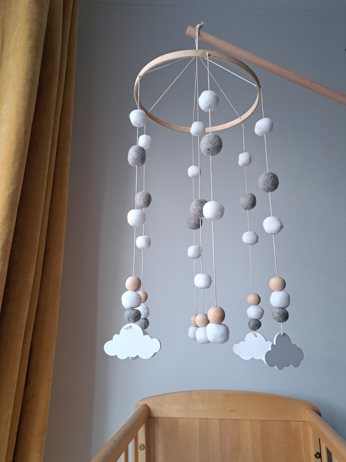 Decorative mobile with hanging balls on a wooden stand against a light gray wall.