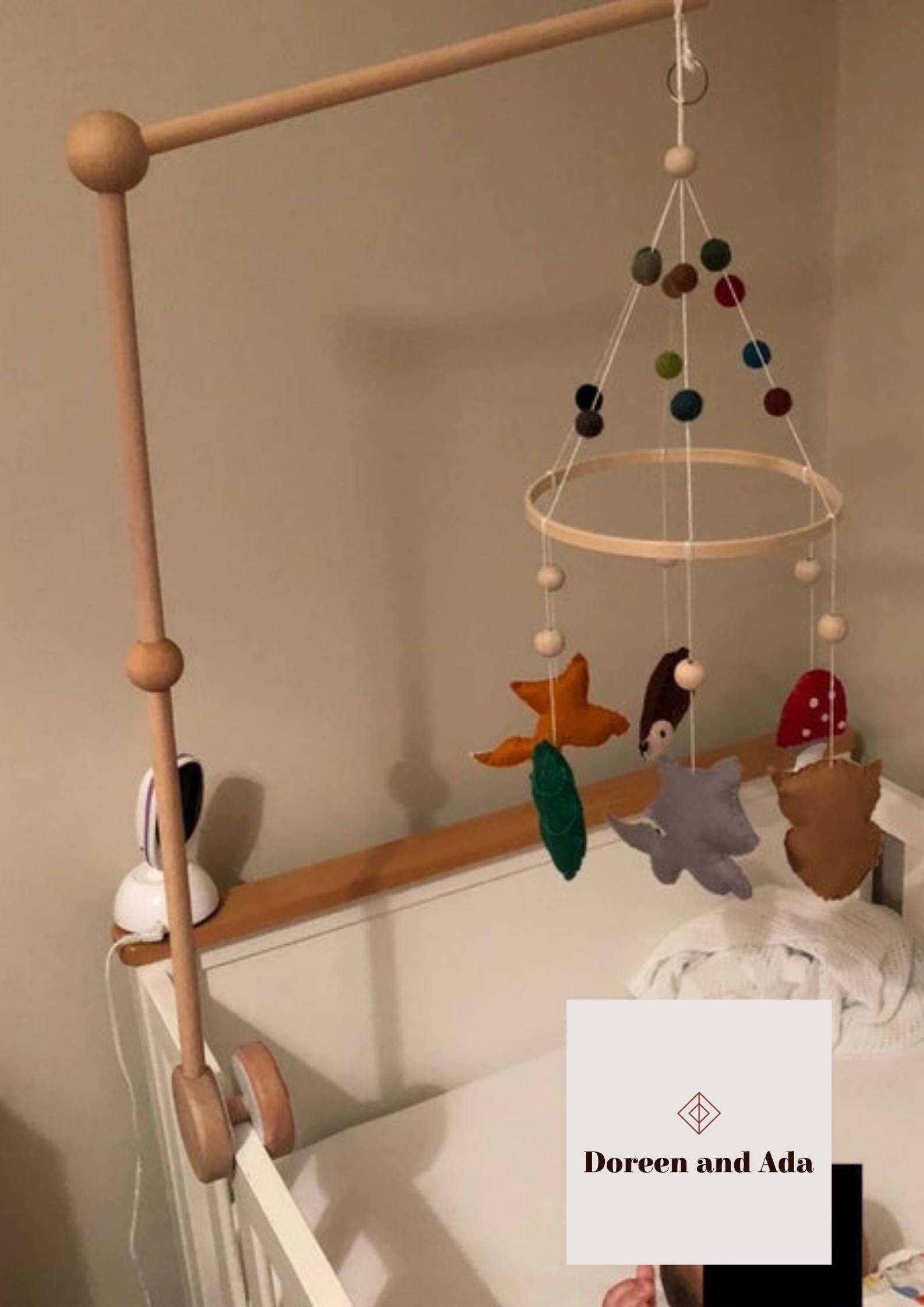 Wooden baby mobile bracket holding mobile above nursery cot
